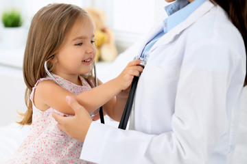 Fototapeta premium Doctor examining a little girl by stethoscope