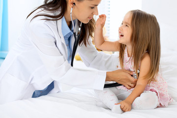 Obraz na płótnie Canvas Doctor examining a little girl by stethoscope