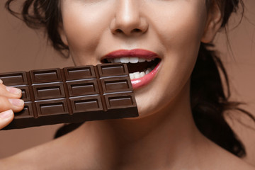 Beautiful girl with chocolate on brown background