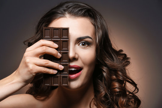 Beautiful girl with chocolate on dark background