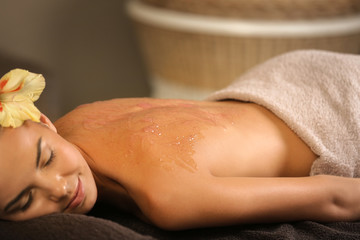 Obraz na płótnie Canvas Young woman undergoing scrub treatment in spa salon