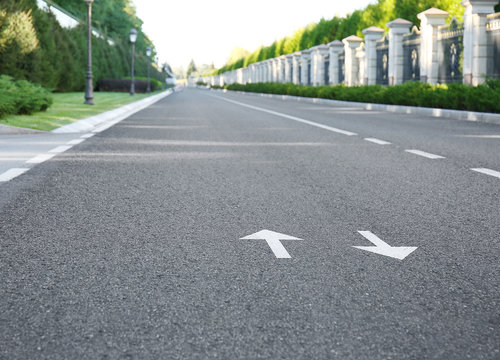 Arrow signs on asphalt road showing direction of movement