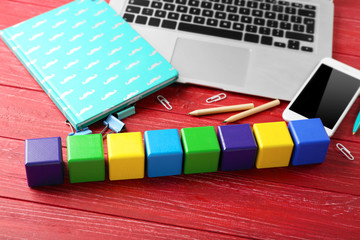 Fototapeta na wymiar Laptop, copybook and wooden cubes on color background