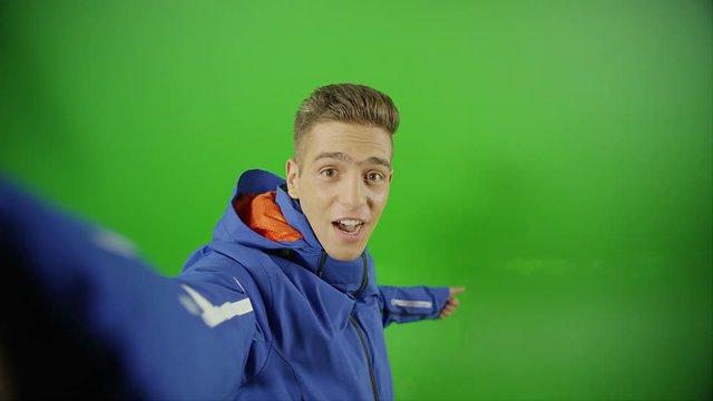 Young boy imitating of taking selfie from a high place on green screen. Demonstrating different ways of emotions and poses. With photo camera flash light. Shot on RED EPIC DRAGON Cinema Camera.