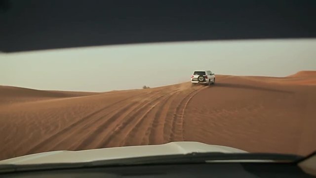 Desert Safari SUVs bashing through the arabian sand dunes. View from the car 3.