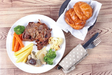Home made ,Pork steak and mixed vegetables with croissants .
