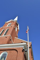 Red brick exterior architecture church belfry and spire with a clear blue sky