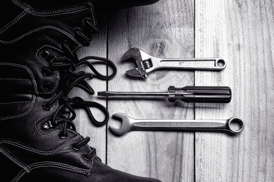 Safety shoes with wrenches and screwdriver tools on wooden