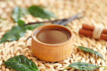 Fototapeta na wymiar Wooden bowl with tea oil on wicker mat