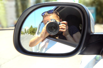 Girl taking photo with camera in moving car