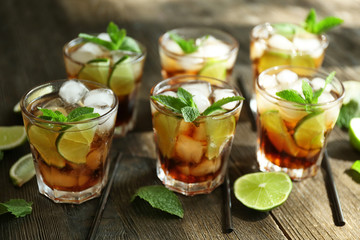 Glasses of cocktail with ice and mint on wooden table closeup