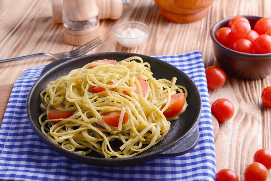 Pasta with cherry tomatoes and avocado sauce on wooden table closeup
