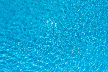 Ripple blue water surface in swimming pool with sun reflection