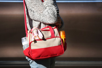 Woman with baby bag standing near a car