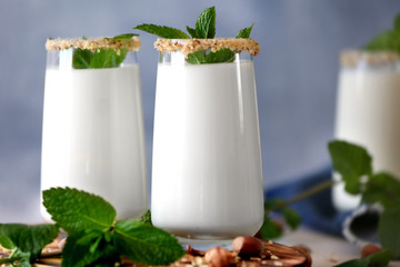 Glasses with delicious nut milk shake and mint on table, closeup