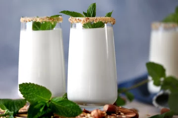 Photo sur Plexiglas Milk-shake Glasses with delicious nut milk shake and mint on table, closeup