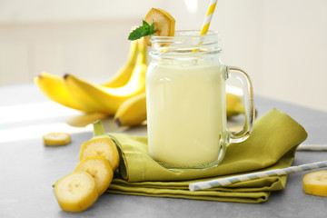 Jug with tasty banana milk shake on table