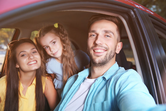 Happy family with daughter taking selfie in car