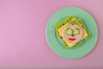 Green plate with funny sandwich on pink background