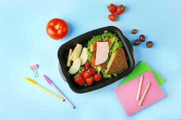 Lunchbox with tasty dinner and stationery on blue background