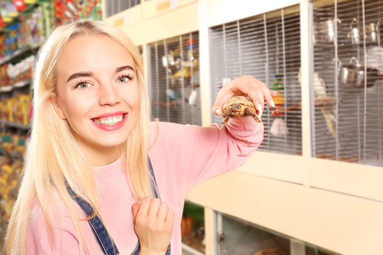 Portrait Of Beautiful Young Woman Holding Cute Turtle In Pet Shop