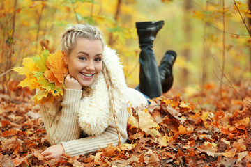 Beautiful girl with bunch of leaves in autumn park