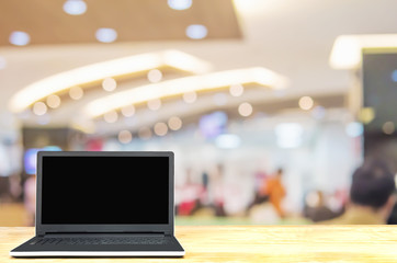 Laptop on white wooden table top over blurred business customer service room with some of people