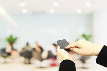 A man is using telephone over blurred bokeh light in office and people background