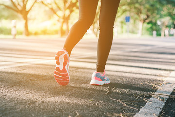 Young lady running on road closeup on shoe., at time sunset