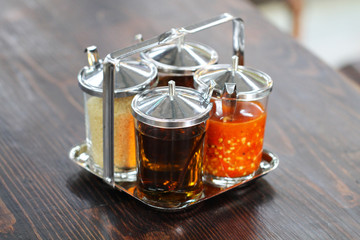 Thai style Seasoning, fish sauce, sugar, vinegar and chilli powder in glasses and aluminum cover on wooden brown table, street food restaurant