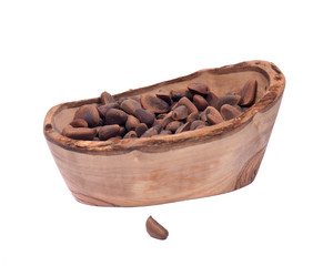 Organic pine nuts in shell in olive wood bowl isolated on white background