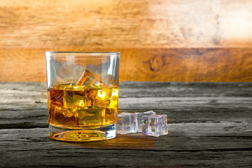 glass of whiskey with ice on a wooden table