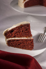 Slice of Red Velvet Cake on Dessert Plate with Cake in the Background