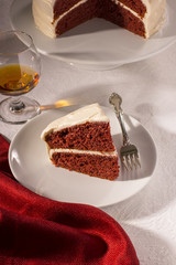 Slice of Red Velvet Cake on Dessert Plate with Cake in the Background