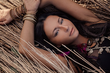 Beautiful young boho woman lying on grass