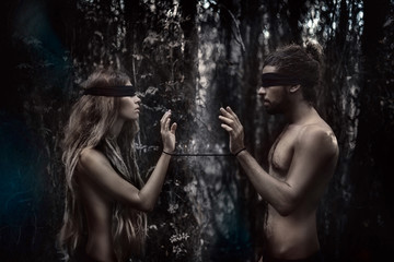 atrractive young man and woman with eyes closed. lost in forest