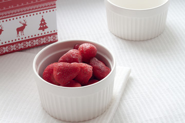 Frozen strawberries in a white cup on a white tablecloth