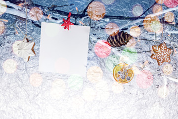 christmas decorations with empty greeting card and homemade gingerbread cookies on bare tree branches 