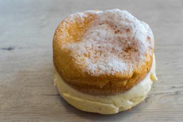 Cake with white pudding and sugar on top on a wooden background.