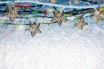 christmas holiday lights hanging on bare tree branches against blurred silver background