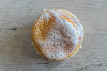 Cake with white pudding and sugar on top on a wooden background.