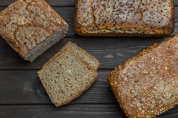 Homemade bread with seeds on dark brown wooden background.