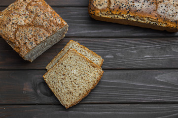 Homemade bread with seeds on dark brown wooden background.