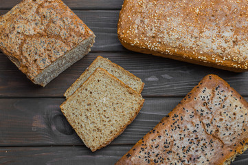 Homemade bread with seeds on dark brown wooden background.