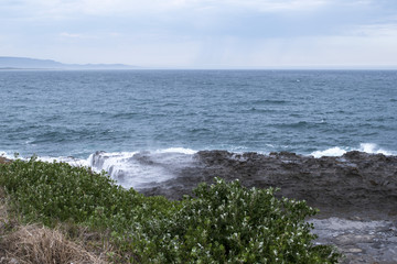 Coastal landscape with sea waves and large boulders on beach
