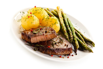 Grilled beef steaks and asparagus on white background