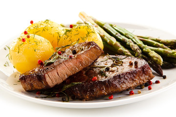 Grilled beef steaks and asparagus on white background