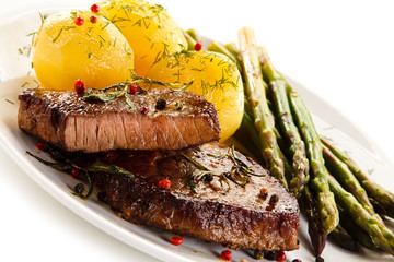 Grilled beef steaks and asparagus on white background