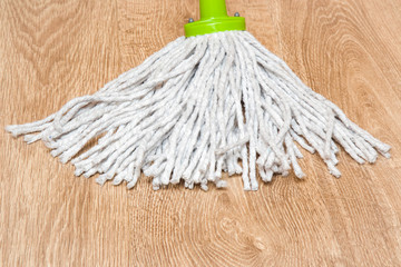 Wooden floors washing with mop in the room. Regular clean up. Maid cleans house.
