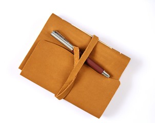 notebook  in brown leather cover, brown pen  isolated on white background